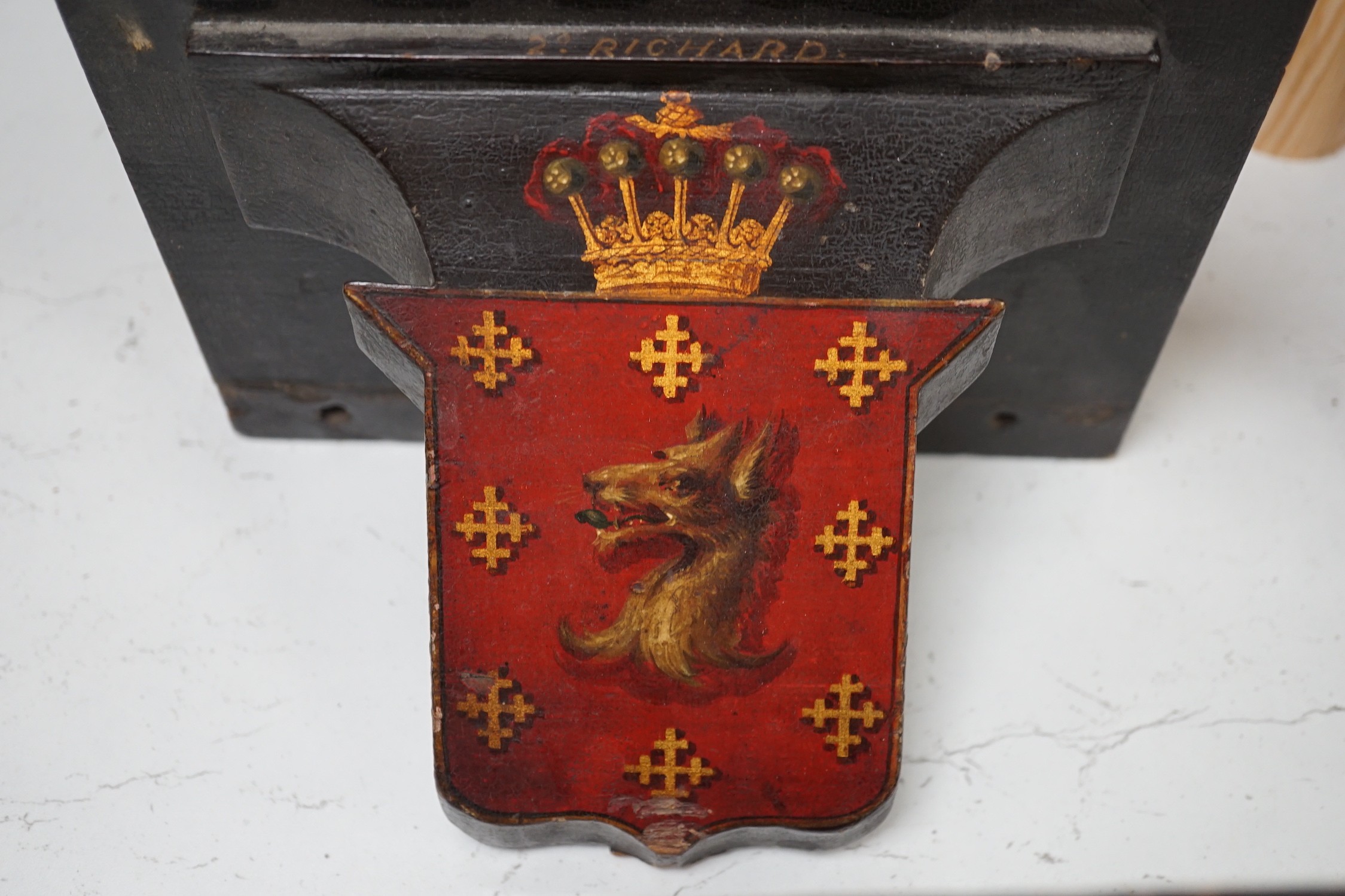 Four 19th century painted and ebonised heraldic wall brackets together with a 19th century armorial plaque